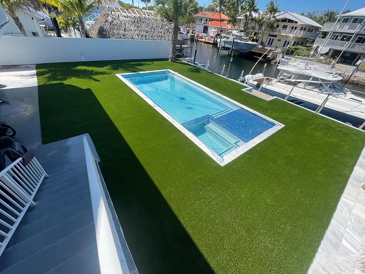Canal-front pool with artificial turf, boats docked alongside