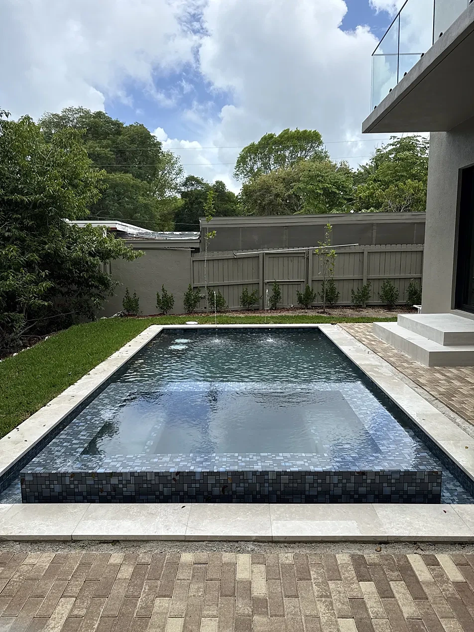 Raised spa with deck jets, travertine coping and brick paver patio
